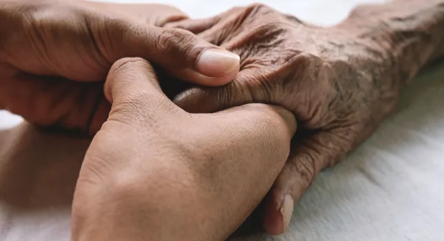 image of an elderly senior lady looking sad and down, a youthful pair of hands holding a senior's hands, an elderly woman hugging her loved one from behind while he sits on a wheelchair