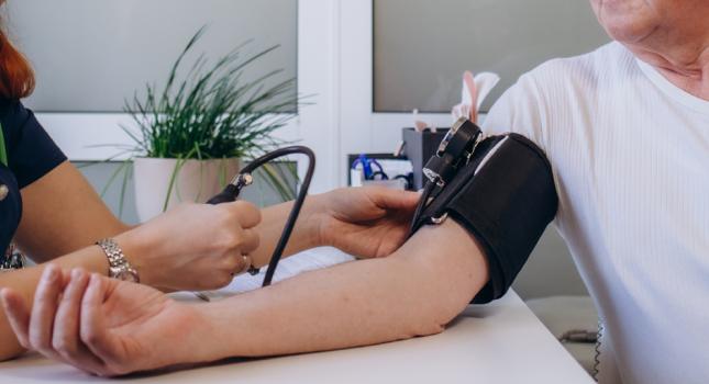 nurse taking the blood pressure of an elderly man